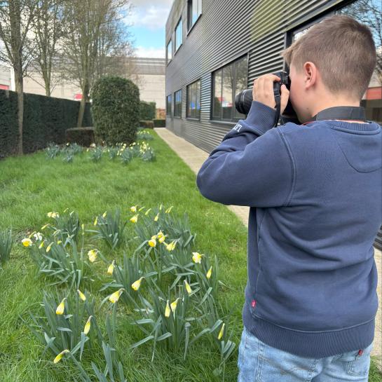 Leerling van Klavertje vier bezig met foto's tijdens zijn stagedag bij de dienst Communicatie